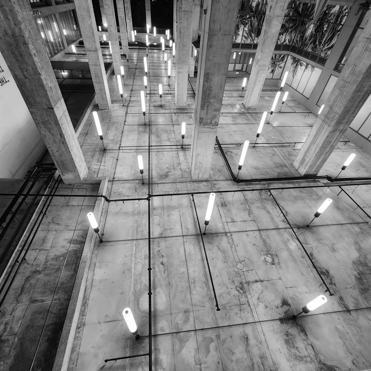 Abstract work by Mac Beach presenting an inverted black-and-white view of exposed concrete columns, conduits, and glowing linear lights beneath a covered walkway in Fort Lauderdale, Florida, 2025.