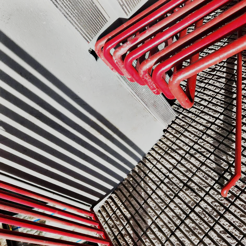 Abstract work by Mac Beach capturing vivid red handrails, striped shadows, and intersecting metal grids in a sharply angled composition in downtown Fort Lauderdale, Florida, 2023.