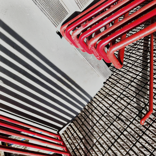 Abstract work by Mac Beach capturing vivid red handrails, striped shadows, and intersecting metal grids in a sharply angled composition in downtown Fort Lauderdale, Florida, 2023.