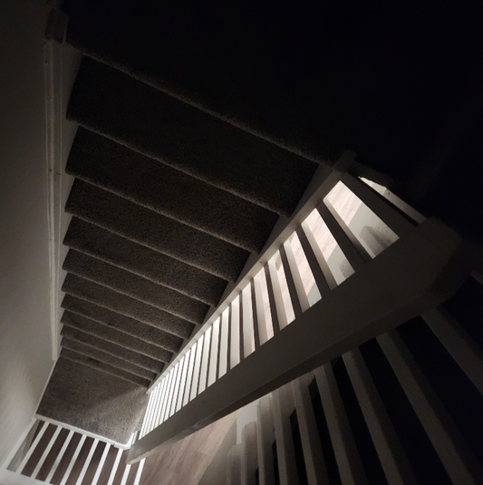 Abstract work by Mac Beach capturing an upward view of an illuminated railing and layered staircase inside a townhouse in Delray Beach, Florida, 2026.